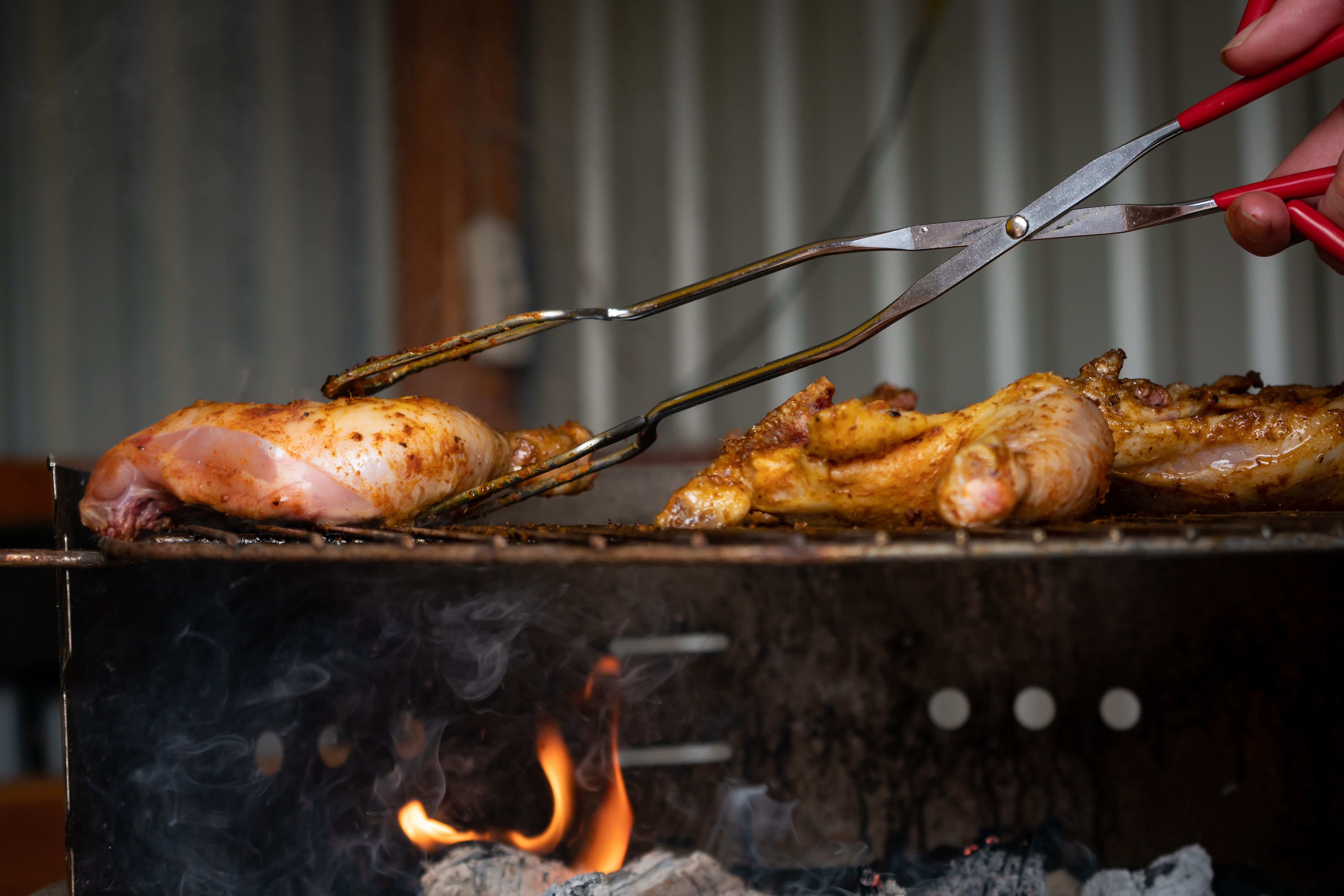 Chicken pieces cooking on a grill.