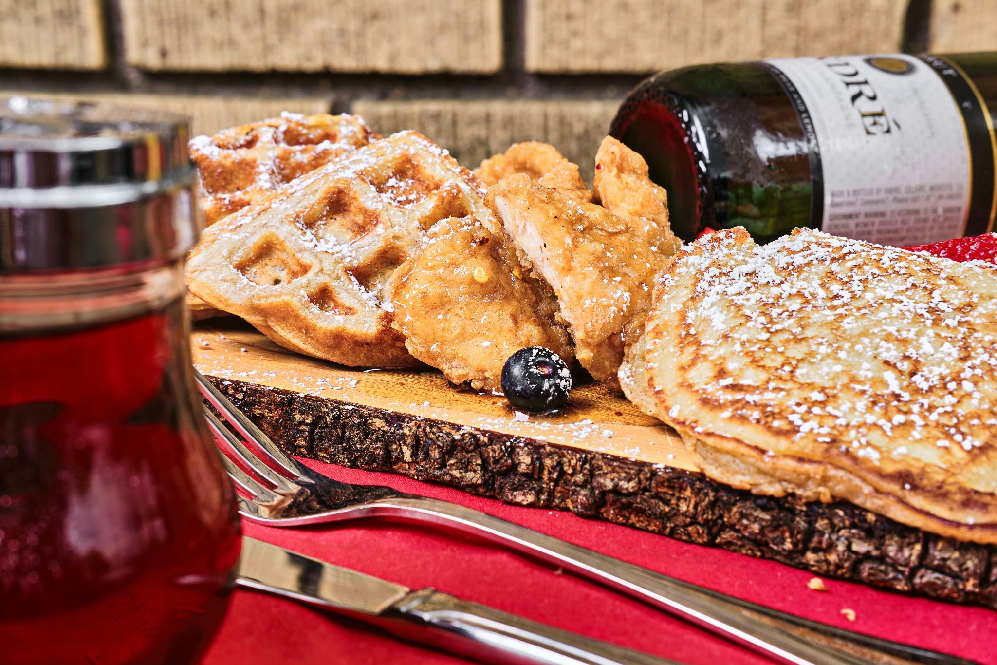 Fried chicken and waffles dusted with powdered sugar on a wooden serving board.