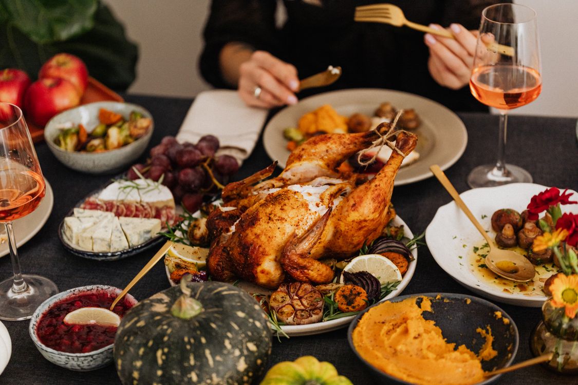 Roast turkey on a white platter with vegetables and side dishes on a dining table.