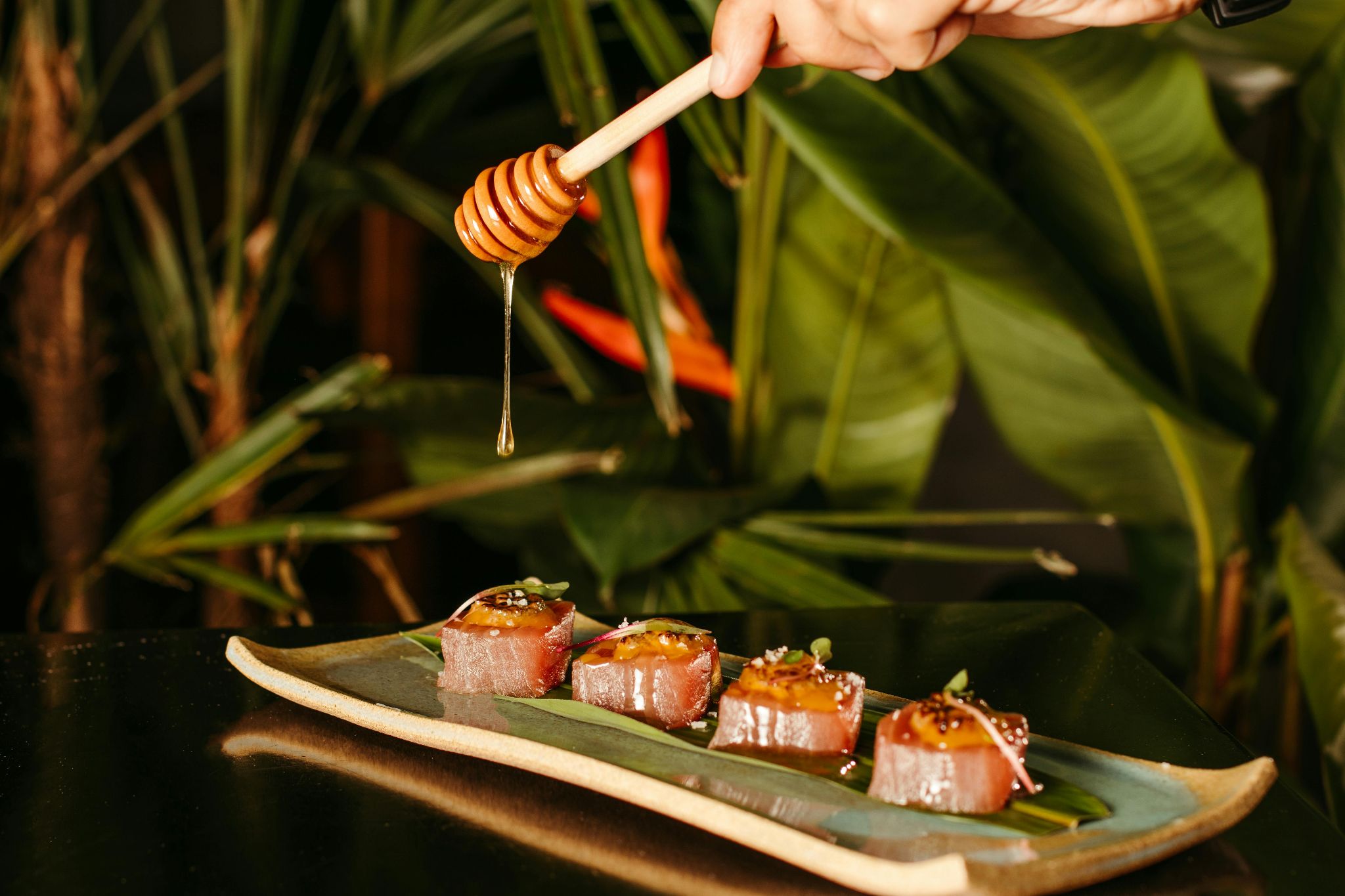 Wooden dipper held above plated fish bites.