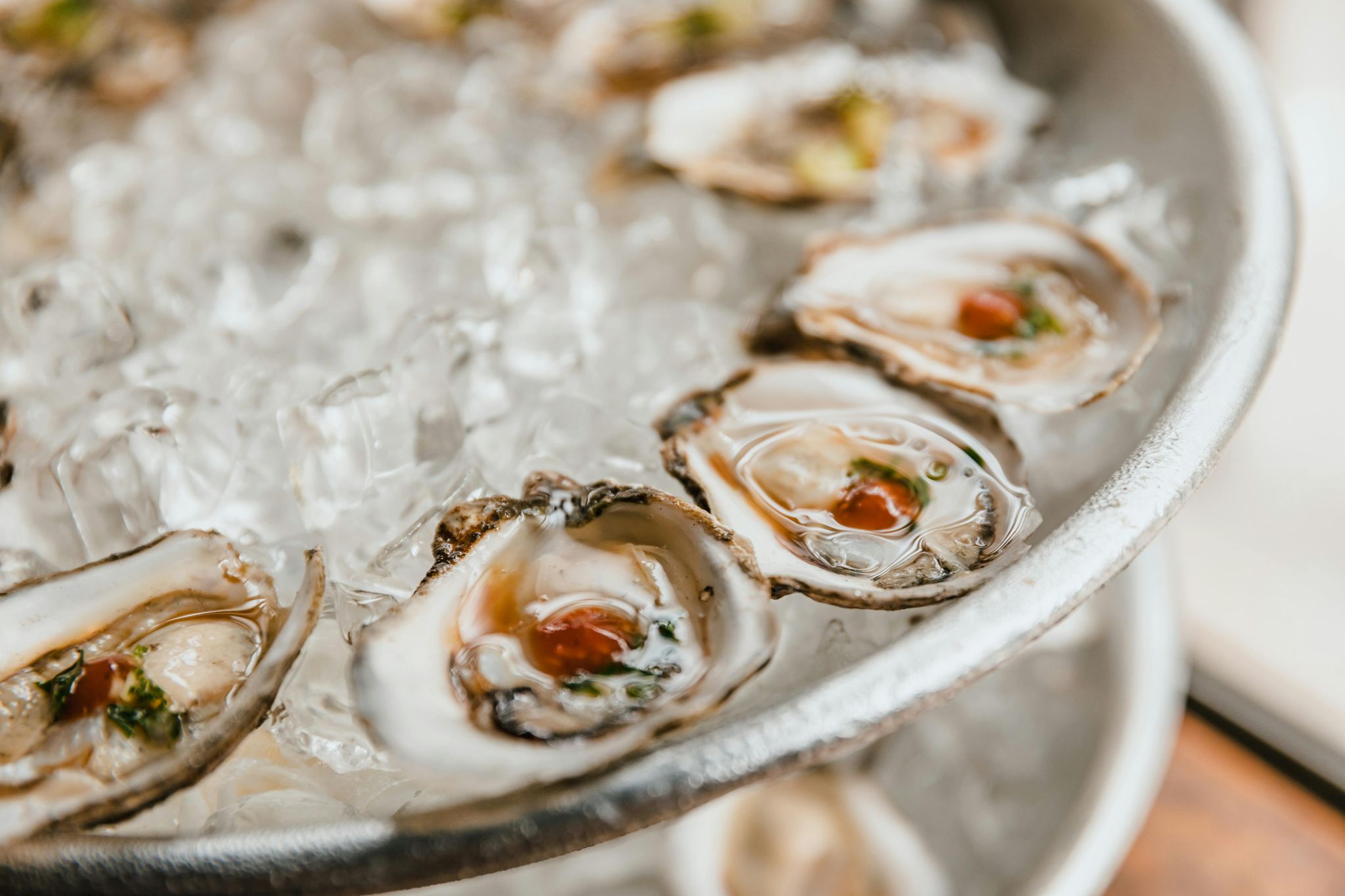Open oysters on ice beside a sauce.