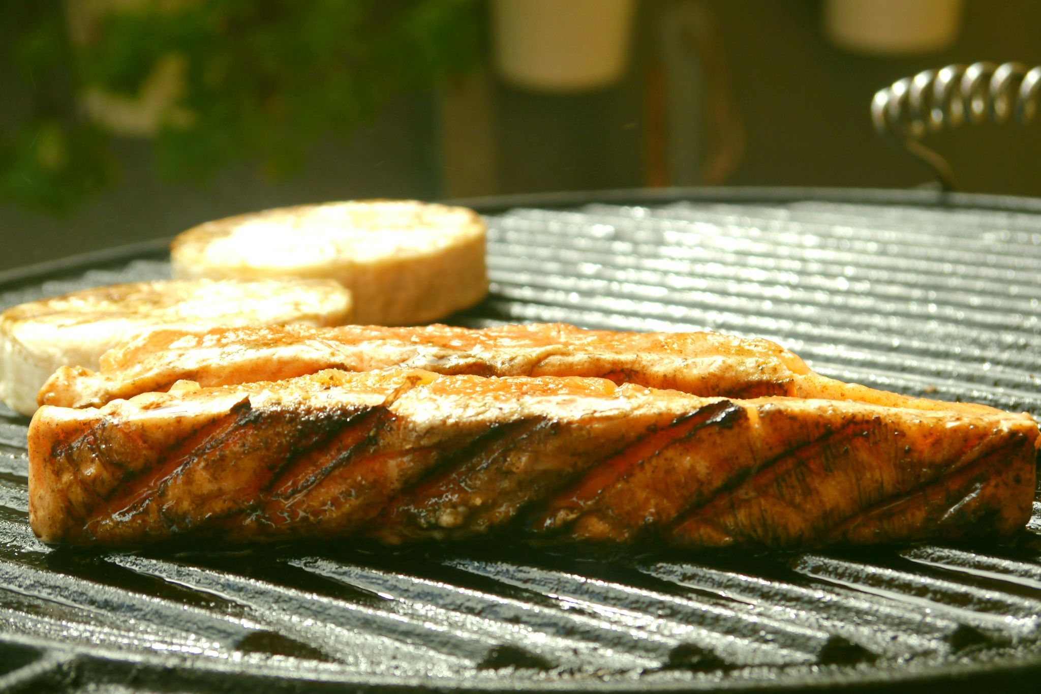 Salmon fillet and lemon on grill grates.