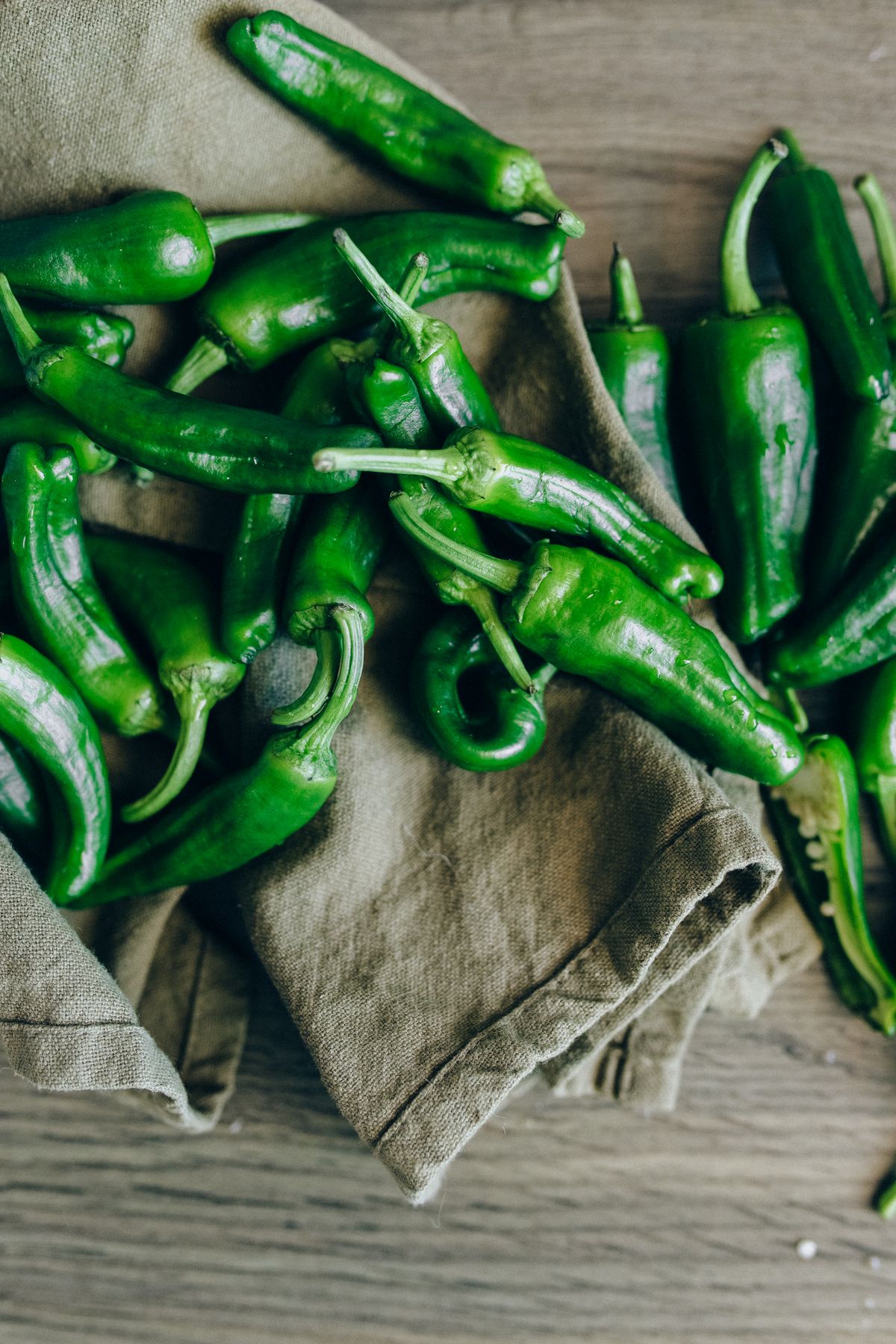 Green chili peppers on a gray cloth.