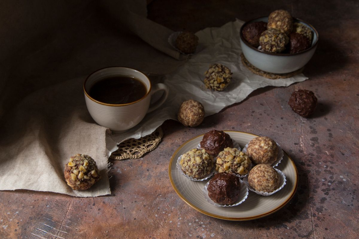 Chocolate snack balls beside a cup of coffee.