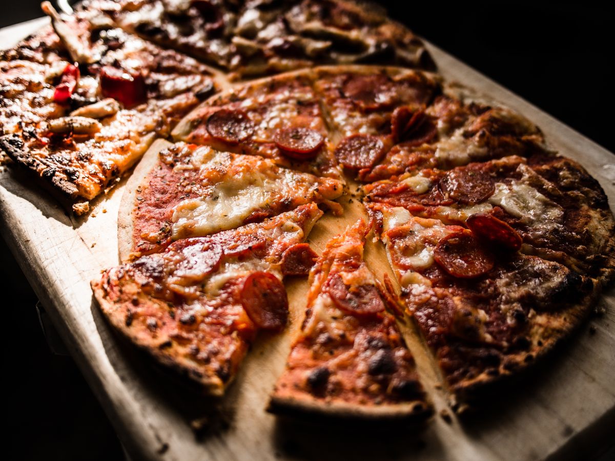 Pepperoni pizza cut into slices on a wooden board.