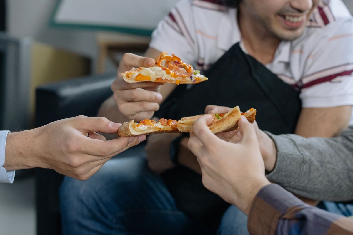 People holding pizza slices together.
