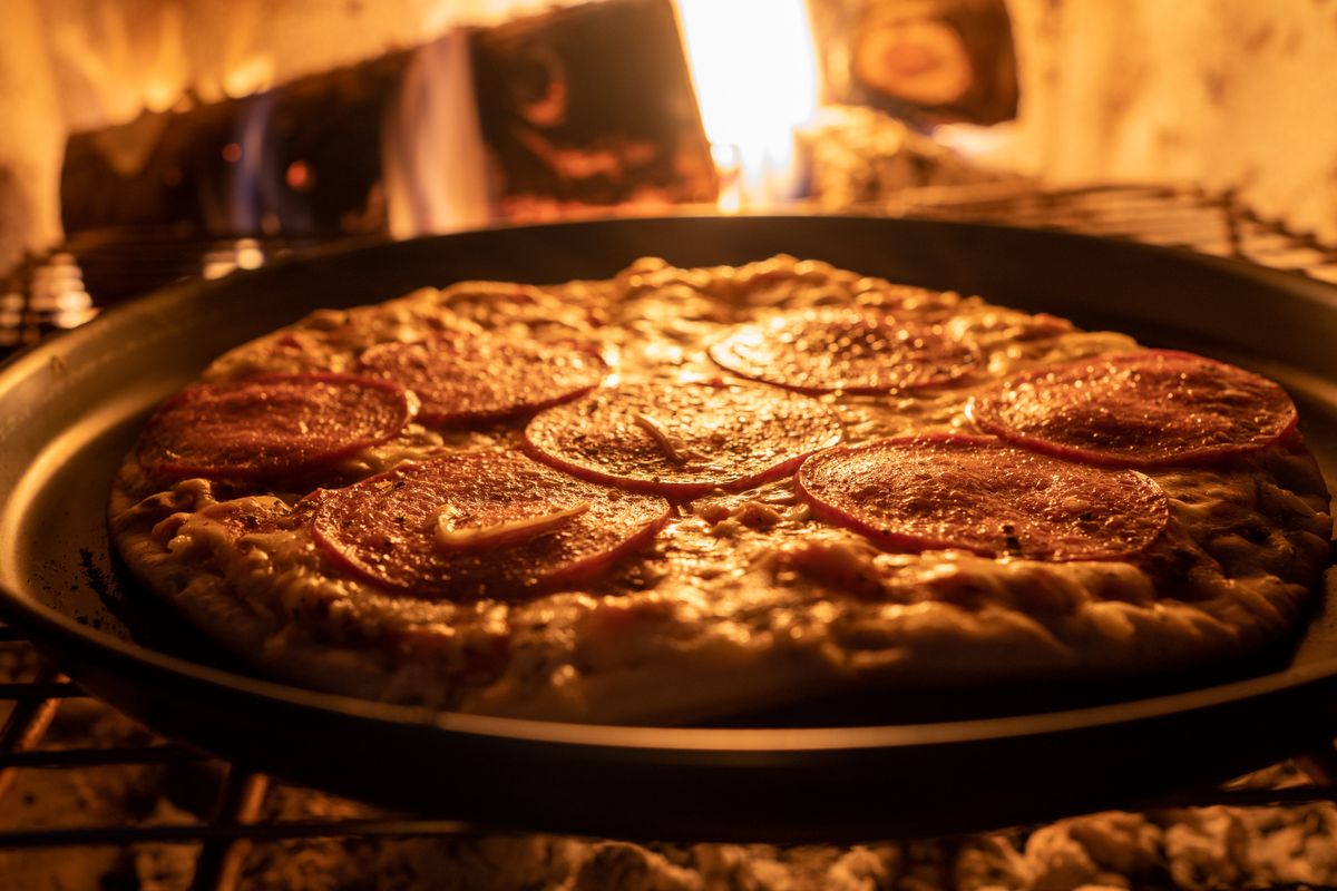 Pepperoni pizza in a pan inside an oven.