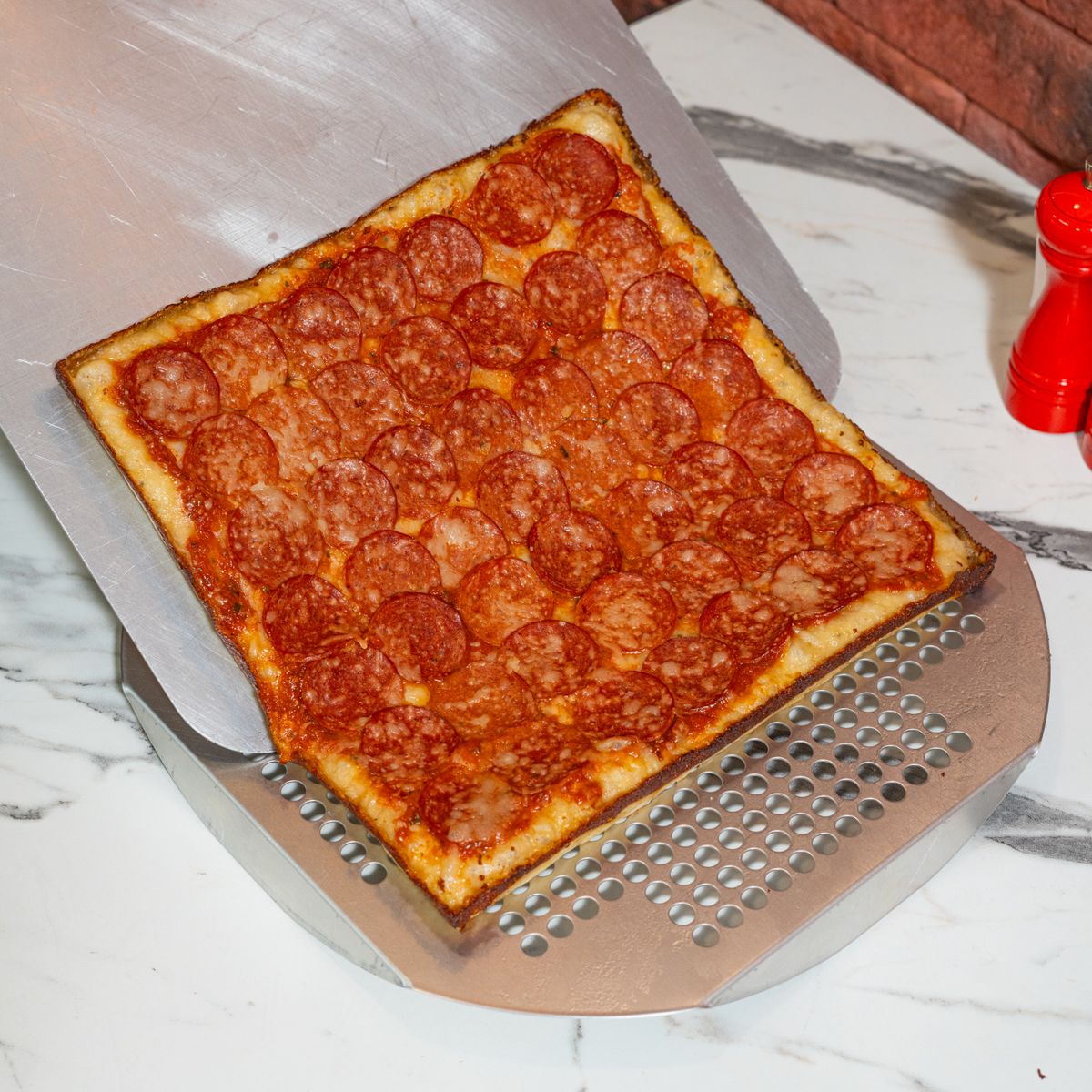 Square pepperoni pizza on a metal pizza peel.