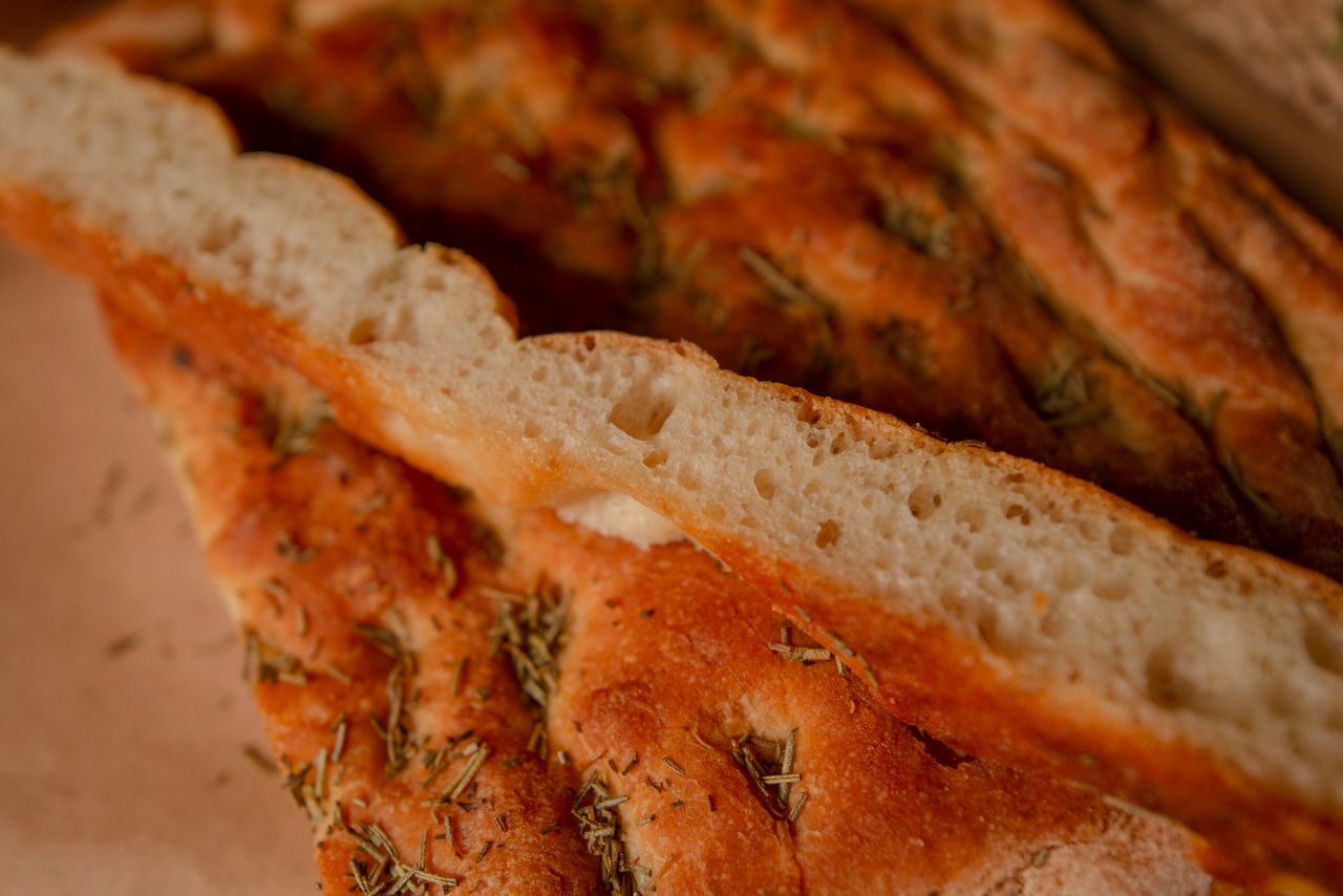 Sliced focaccia with herbs and a browned crust.