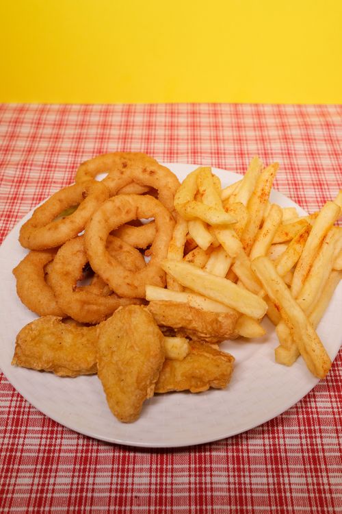 Nuggets, fries and onion rings on a plate.