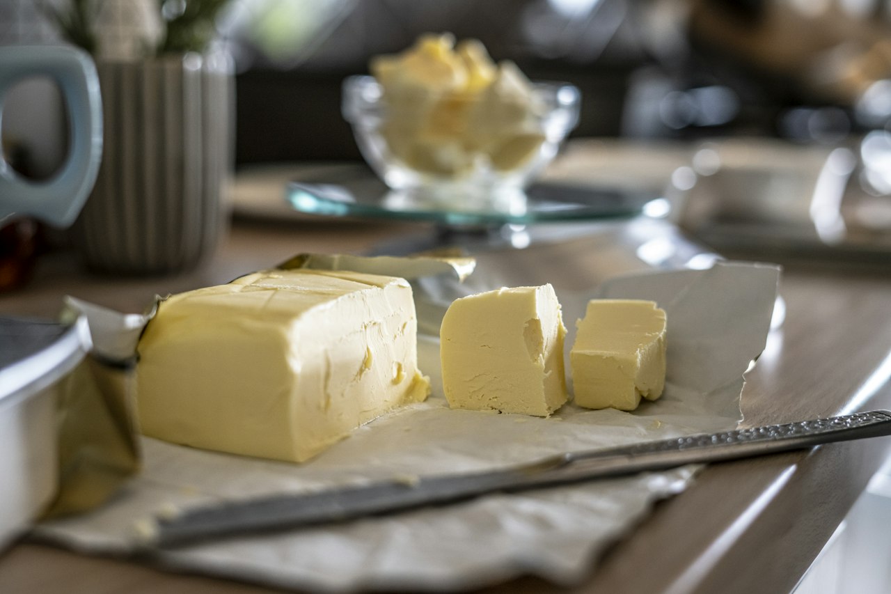 Sliced butter rests on paper beside a knife.