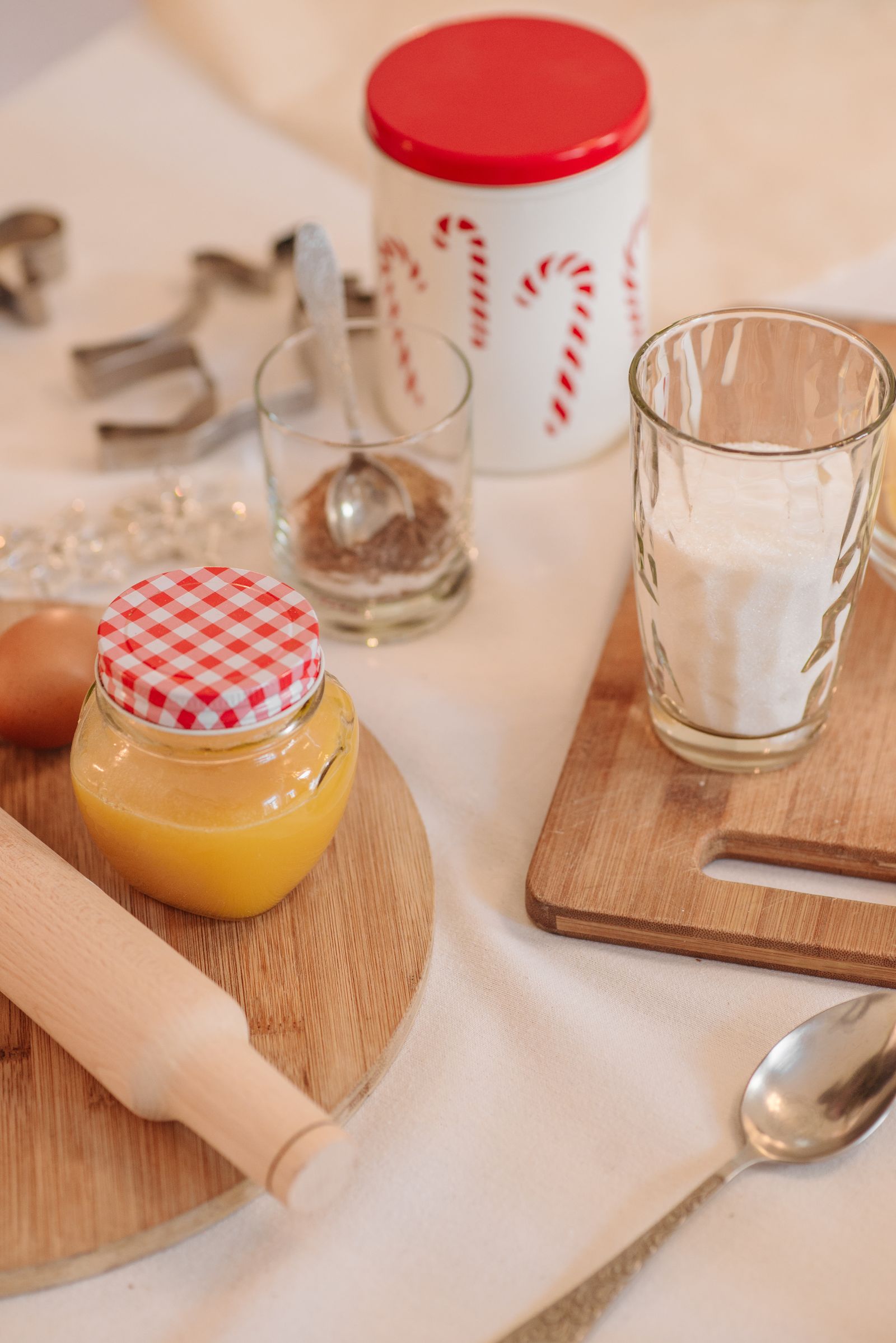 An egg, jars, flour, cookie cutters and a rolling pin sit on a table.
