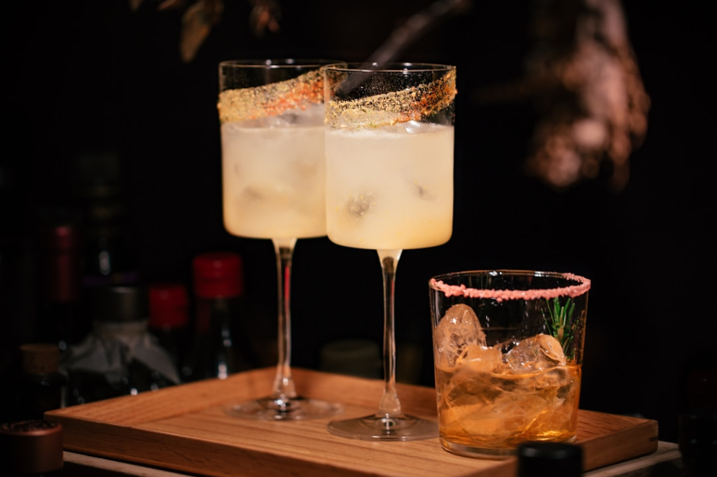 Cocktails in stemmed and short glasses on a wooden tray.
