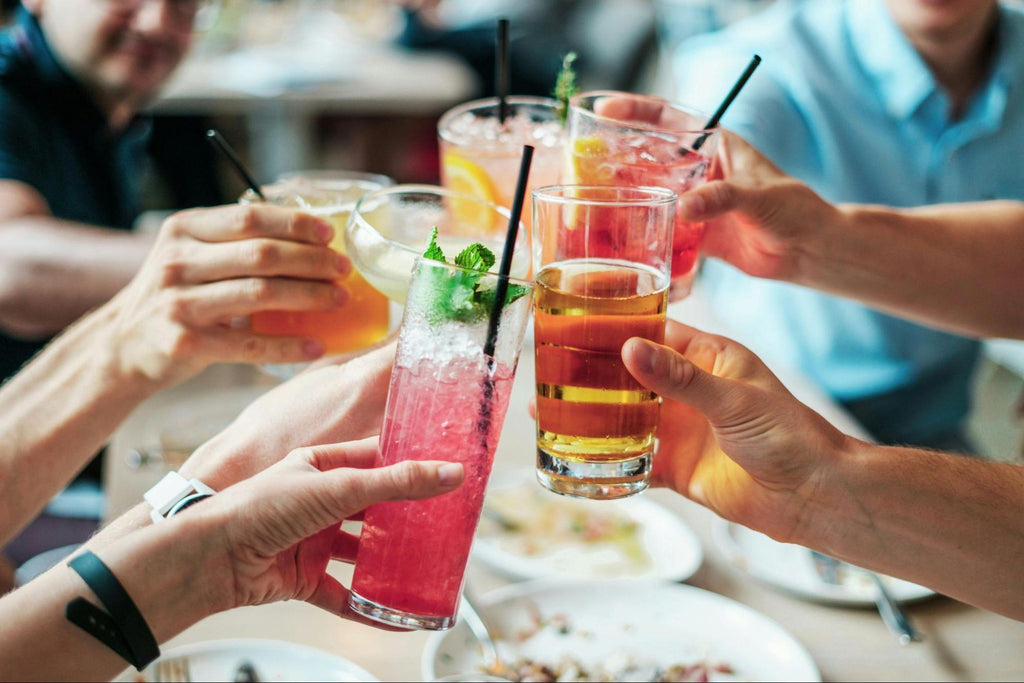 A group raising colorful drinks together at a table.