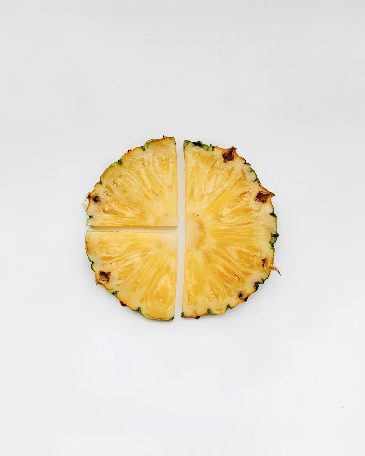 Sliced pineapple rests on a white surface.
