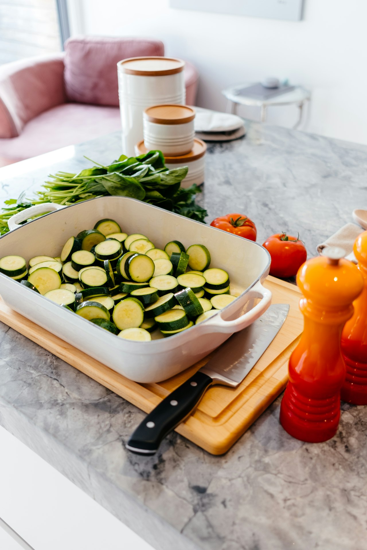 Sliced zucchini fills a white baking dish on a kitchen counter.