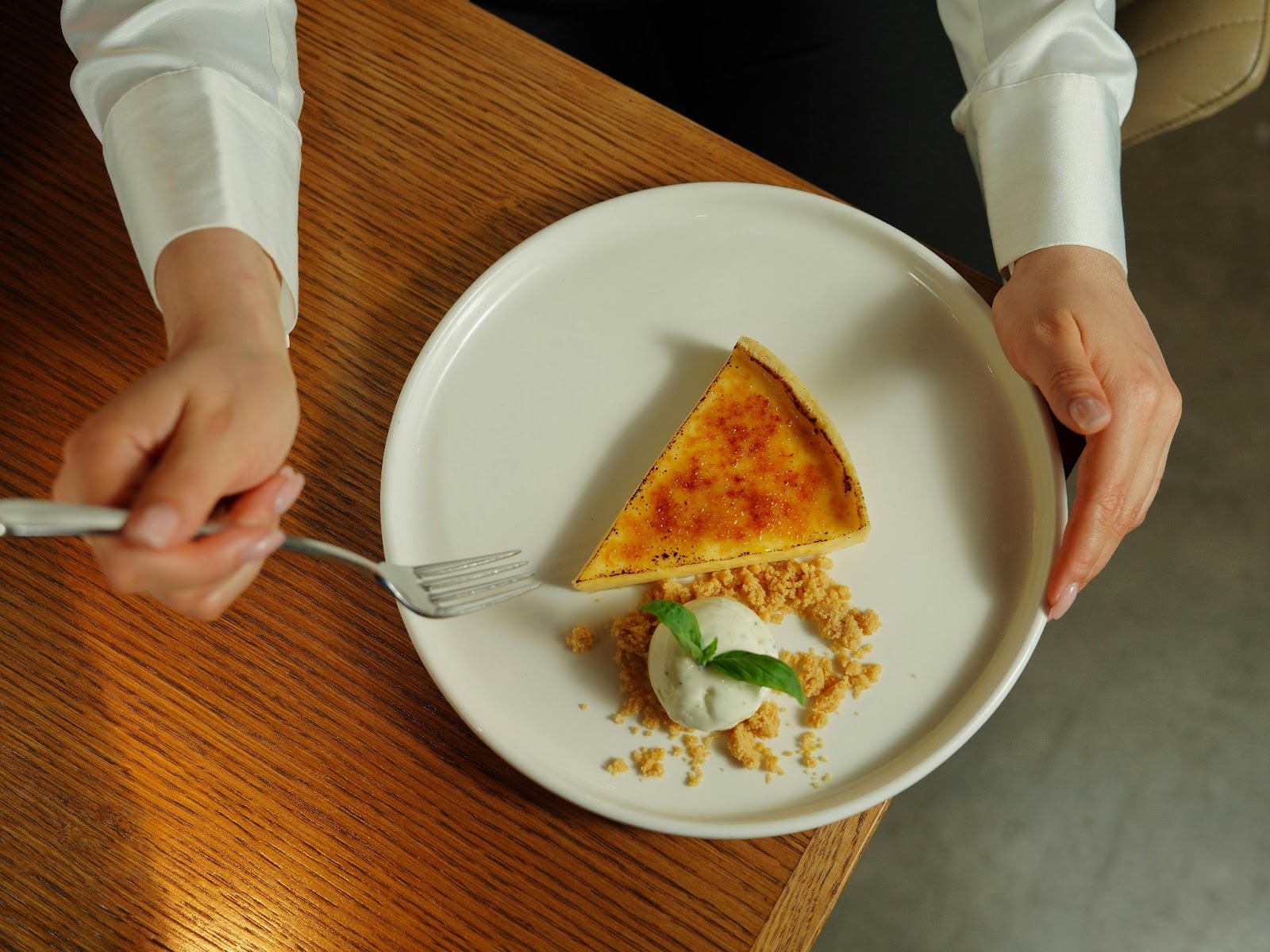 A slice of crème brûlée tart beside ice cream on a white plate.