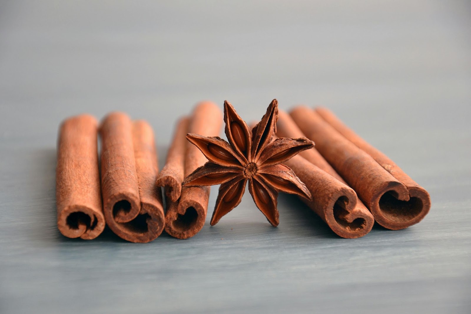 Star anise resting against cinnamon sticks.