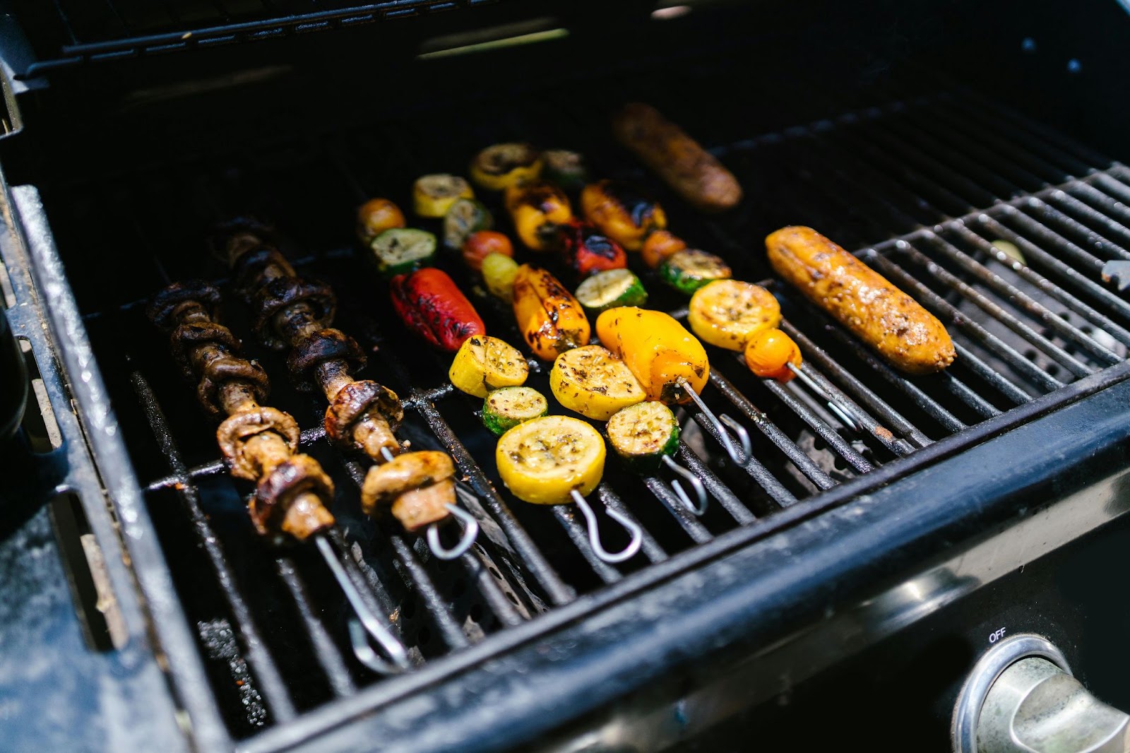Vegetable skewers and other food cooking on a grill.