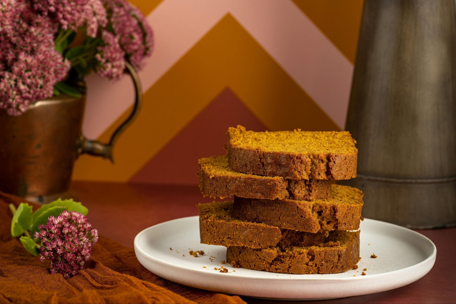 Slices of pumpkin bread stacked on a white plate.